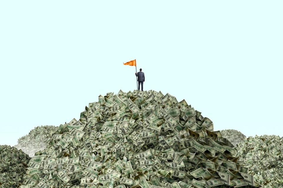 A person holding an orange flag on top of a pile of money.