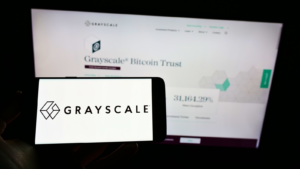 Person holding a mobile phone with the logo of the US cryptocurrency company Grayscale Investments LLC on the screen in front of the web page. Focus on the phone display. Unedited photo. GBTC stock