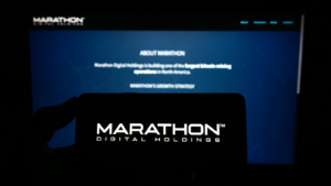 Person holding a mobile phone with the logo of the American company Marathon Digital Holdings Inc. on the screen in front of the web page. Focus on the phone display. Unedited photo. MARA action