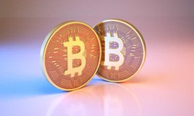 Bitcoin digital currency sitting on metallic blue and pink background